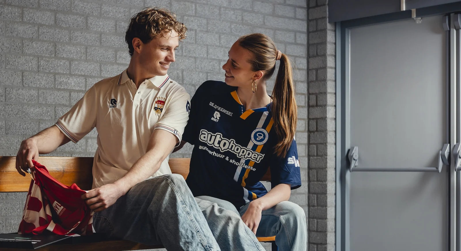 Two fans on a bench in their mystery shirts